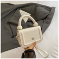 Detail of off-white lychee grain leather bag with unique thick handle and metal logo - White