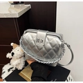 Détail du sac argenté matelassé avec texture métal, fermoir pivotant et bandoulière chaîne - Argent avec pendentif