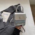 Dettaglio della fibbia a farfalla in argento e catena di perle sulla mini borsa a tracolla - Celeste