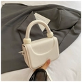 Detail of off-white lychee textured handbag featuring unique spherical handle accents - White