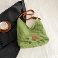 Close-up of green woven tote bag with brown leather strap and logo detail on white fabric - Green