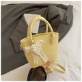 Close-up of pale yellow leather bucket bag with pearl heart charm and lace ribbon detail - Yellow