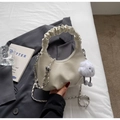 Detail der cremeweißen Cloud-Bag mit Raffung und silberner Kette auf grauem Blazer - Off-White mit Anhänger