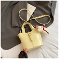 Creamy yellow bucket bag in matte leather with adjustable strap and plush bear charm - Yellow
