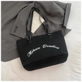 Dettaglio della borsa tote in tela nera con scritte bianche e spalline in pelle premium - Nero