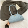 Dettaglio borsa baguette blu con stampa coccodrillo e logo su sfondo di giacca elegante - Blu