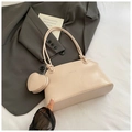 Close-up of a cream underarm bag featuring a small heart-shaped charm and logo detail - With Ornament / Pink