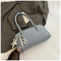 Detail of light blue denim Boston bag with silver star and balloon dog charms on a grey suit - Blue