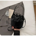 Détail du sac seau noir avec gaufrage crocodile, fermeture à cordon et logo de la marque - Noir
