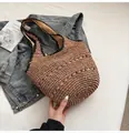 Detail of hand-woven straw tote bag with wavy cut-outs and black fabric shoulder straps - Khaki