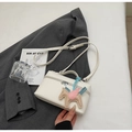 Elegante weiße Tasche aus Lychee-Leder mit Pegasus-Anhänger auf grauem Anzug-Hintergrund - Off-White mit Anhänger