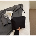 Detail der minimalistischen schwarzen Nylon-Schultertasche mit Reißverschluss auf weißem Bett - Schwarz Stoff