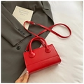 Primer plano detallado de un bolso de cuero rojo con asas dobles y logotipo grabado - Rojo