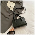 Detalle del bolso bandolera de cuero negro con logo grabado sobre tela de traje gris - Negro