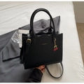 Dettaglio borsa in pelle nera con bordi smerlati e logo del marchio dorato inciso - Nero