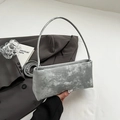 Dettaglio di una borsa baguette grigio argento con texture metallica e manico sottile - Argento