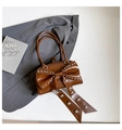 Brown vintage style tote bag with large bow and silver rivet accents in flat lay - Brown