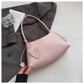 Dettaglio della borsa sottobraccio rosa intrecciata con nappe decorative su lenzuola bianche - Rosa