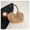 Detail view of woven shoulder bag with colorful bow accents and leather strap in flat lay - Khaki