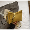 Nahaufnahme der gelben Ledermaserung und des geprägten Logos auf der Handtasche - Gelb
