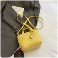 Dettaglio mini borsa in pelle gialla con ciondolo a cuore argento e logo del marchio - Giallo