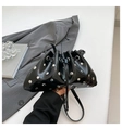 Minimalistische zwarte bucket bag met zilveren studs en trekkoord in een lifestyle setting - Zwart