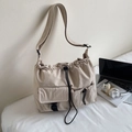 Detail view of beige nylon tote bag with drawstring closure and front flap pockets - Off-white