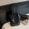 Detail of black faux crocodile leather tote bag shown with laptop and books for scale - Black