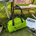 Vibrant green nylon crossbody sports bag with black straps on a lush grass background - Green