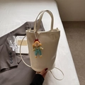 Chic cream-white bucket bag with cartoon charm pendant and versatile straps for women - White