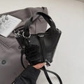 Detail view of black crocodile pattern bucket bag with silver hardware and pendant - Black