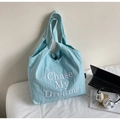 Detail der Chase My Dreams Stickerei und des Druckknopfverschlusses an der hellblauen Tasche - Blau