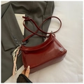 Detail der weinroten Leder-Tote mit silbernem M-Logo und dekorativem Knotanhänger - Mit Ornament / Rot