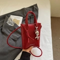 Detail of red pebbled leather shoulder bag with balloon dog charm and knot handle - Wine Red With Pendant
