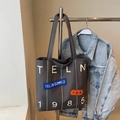 Detailansicht der grauen Canvas-Tragetasche mit weißem TELN 1985 Schriftzug und Patches - Dunkelbraun