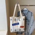 Detail of white canvas tote bag with TELN 1985 lettering and casual patches - Off-white