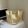 Dettaglio della borsa tote giallo crema con trama a coccodrillo sulla scrivania - Giallo