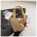 Detail of hollowed bucket bag with geometric cutouts and a small horse pendant - Yellow