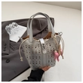 Detail of silver hollowed-out bucket bag with geometric laser cuts and pink charm - Silver