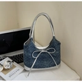 Detail der Jeans-Tasche mit silberner Schleife und Metallic-Besatz auf weißem Schreibtisch - Königsblau