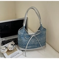 Detail der blauen Denim-Hobo-Tasche mit großer silberner Schleife auf einem Schreibtisch - Denim-Blau