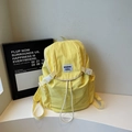 Detail of a bright yellow nylon backpack with drawstring closure and white buckle lid - Yellow