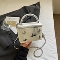 Detail van gebroken witte box-tas met zilveren vlinders en metalen handvat - Off-wit