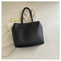 Minimalist large black matte leather tote bag with long strap on knitwear background - Black