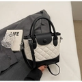 Close-up of quilted bucket bag on grey suit with shoulder strap and metal buckle - White and Black