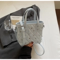 Detailed view of light blue quilted leather bucket bag with metallic rivet studs and strap - Blue