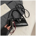 Detail of black underarm bag with silver buckle and braided key charm on a book - Black With Pendant