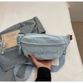 Detalle de la riñonera de cuero sintético azul claro con bordado sobre fondo denim - Azul