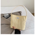 Detalle del bolso plisado crema con etiqueta de marca azul y diseño de textura vertical - Amarillo