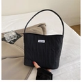 Detalle de bolsa tote de tela plisada negra con textura vertical y etiqueta de marca - Negro